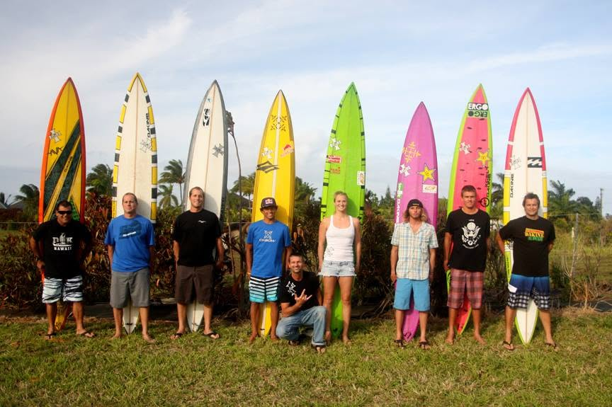 A group of riders standing with colorful big-wave surfboards