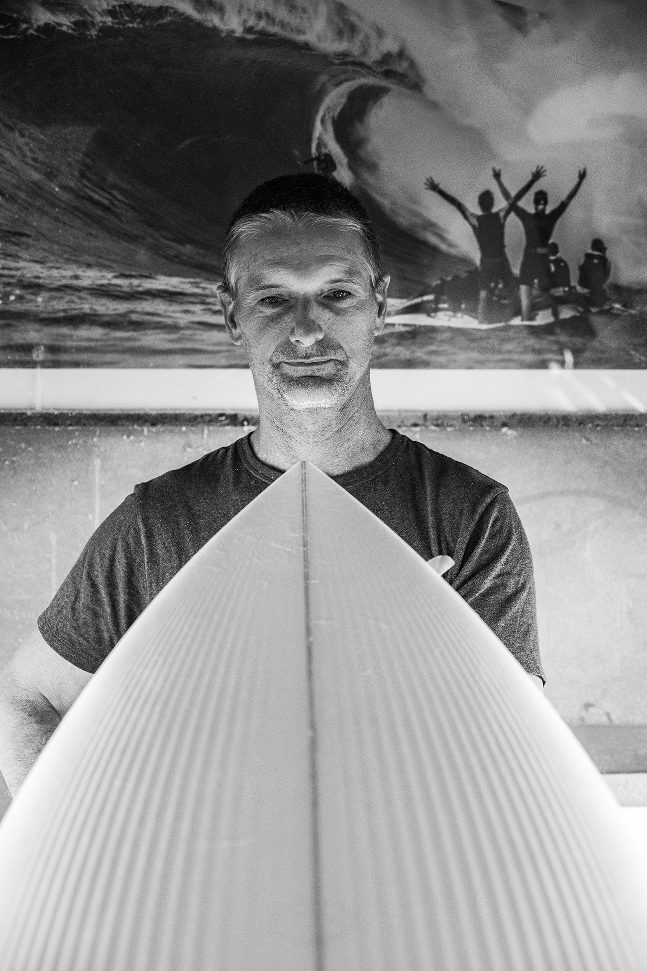 Black-and-white portrait of Sean behind a freshly shaped board